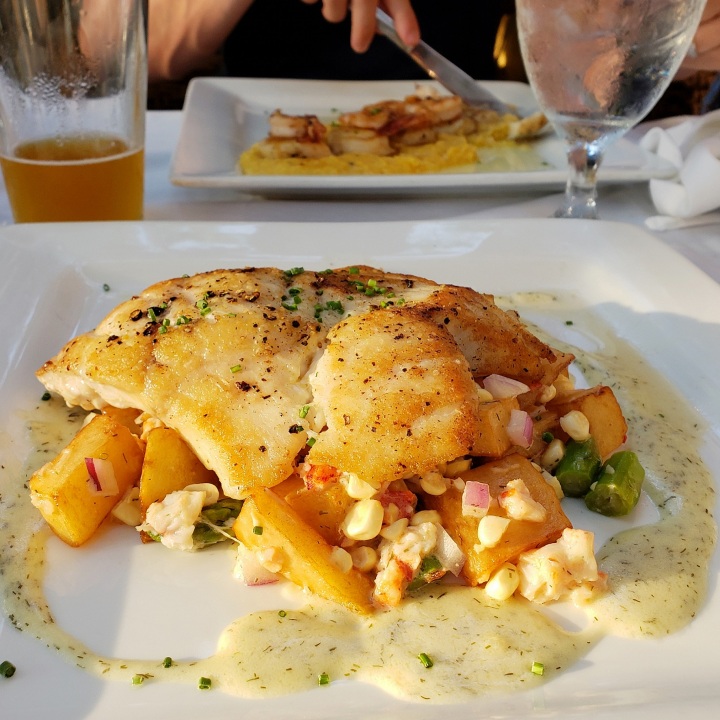 Foreground: Local Grouper (warm dill potato salad, lobster, corn, asparagus); Background: Shrimp and Scallops (yellow stone-ground grits, truffle butter) at Chive Blossom in Pawley's Island, SC